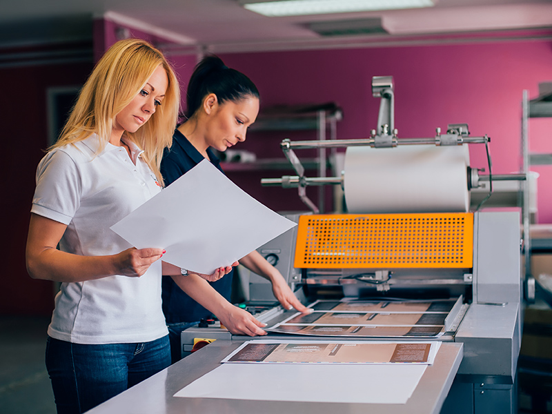 Two women using a hired purchase piece of print finishing equipment